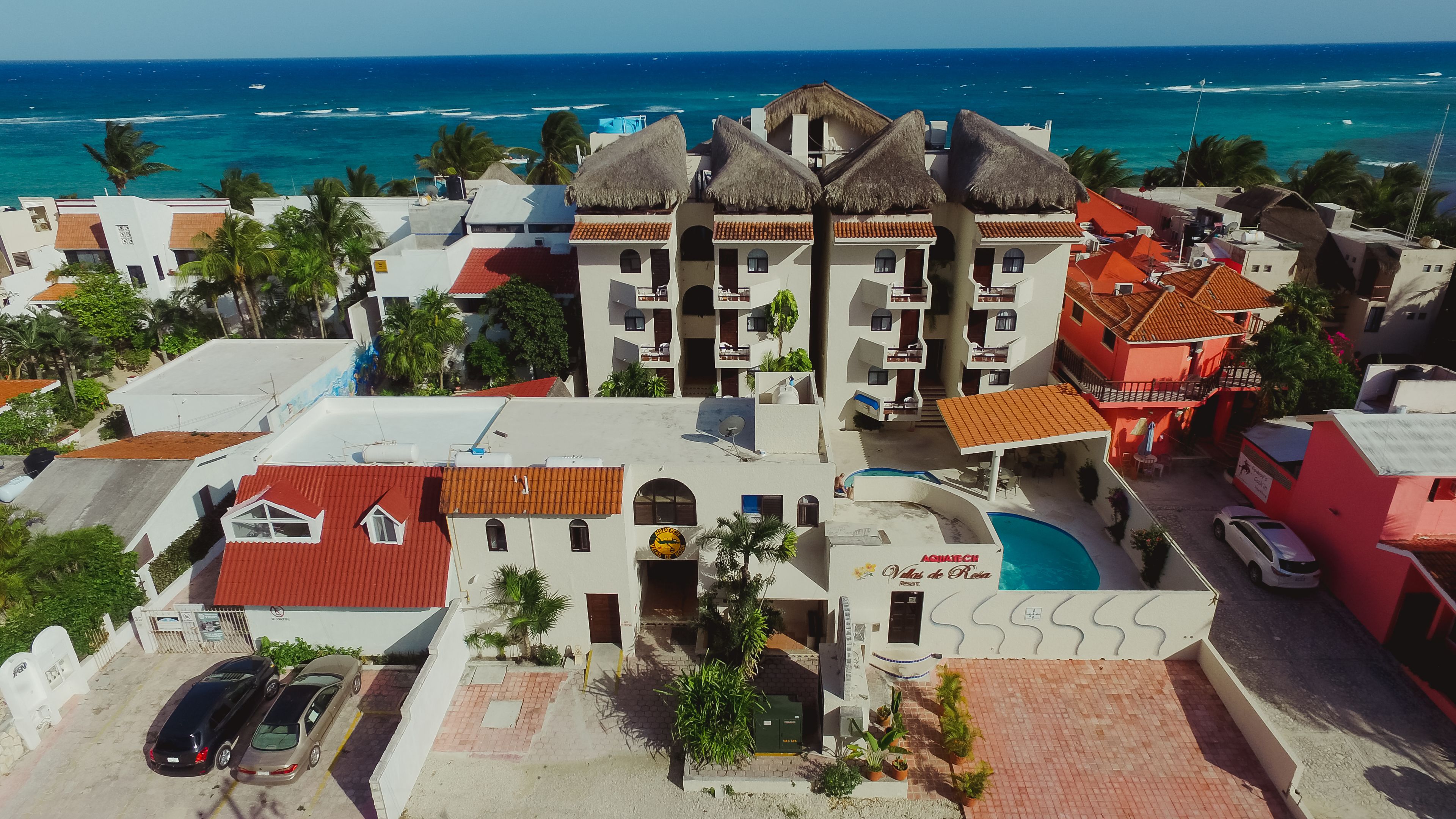 A coastal hotel with multiple buildings, a swimming pool, and a view of the ocean.