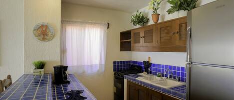 Una cocina con encimeras de azulejos azules, un refrigerador de acero inoxidable y armarios de madera.