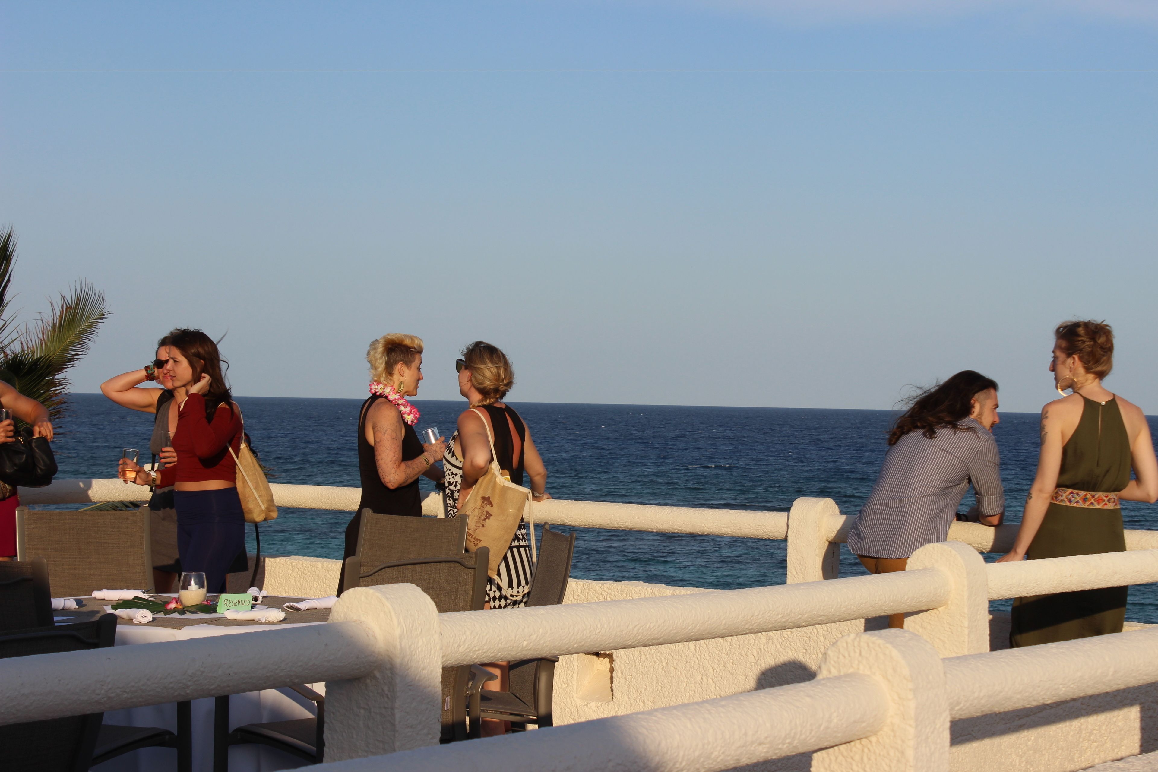 Un área de comedor costera con mesas y sillas, con vista al mar.
