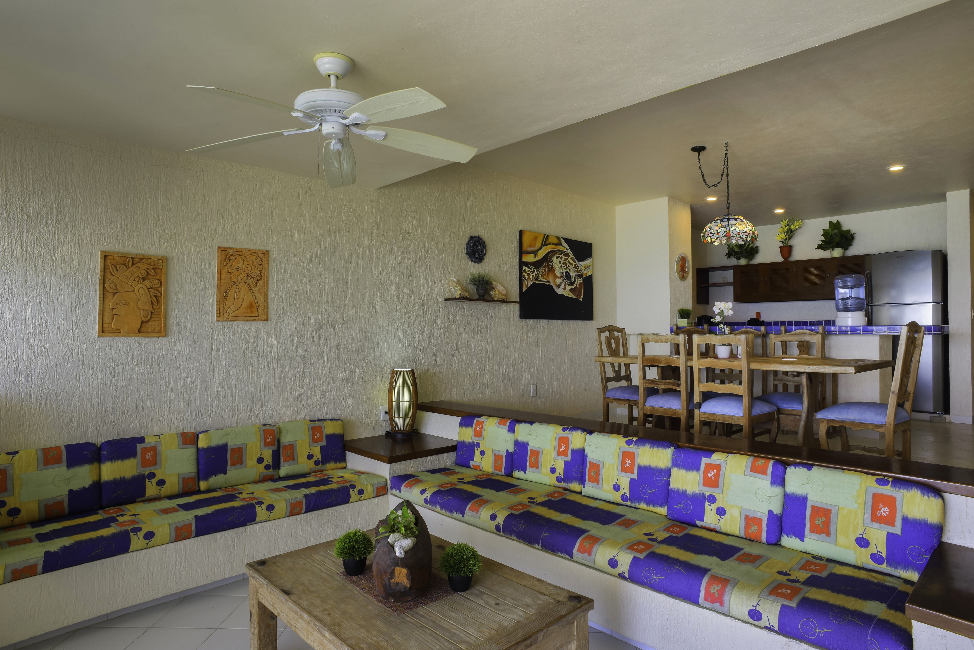 A living room with a sofa, a wooden coffee table, and a ceiling fan.