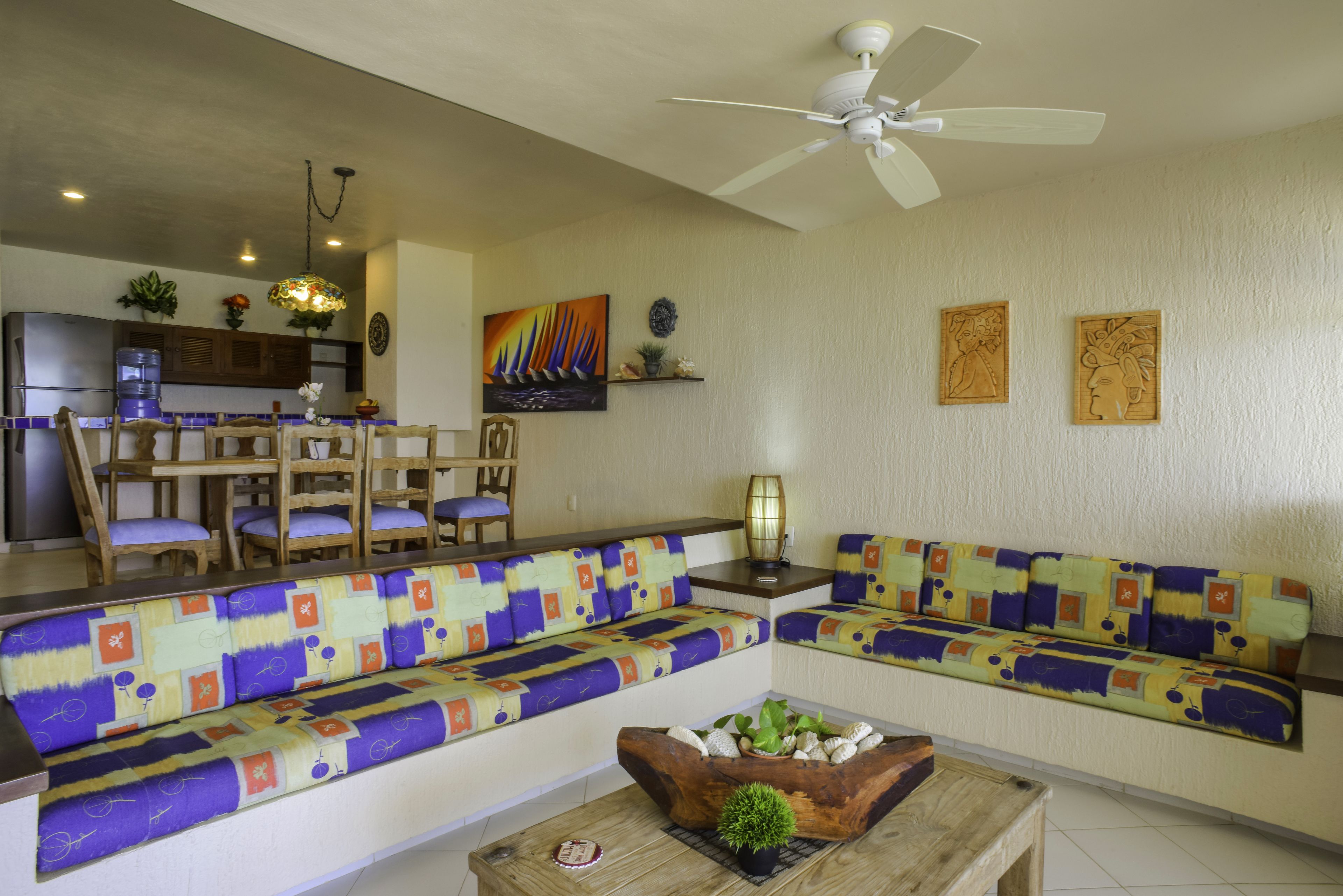 A living room with a sofa, chairs, a coffee table, and a ceiling fan.