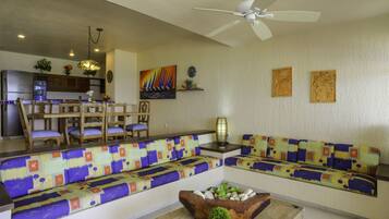 A living room with a sofa, chairs, a coffee table, and a ceiling fan.