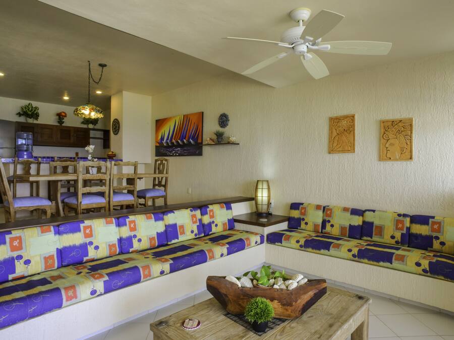 A living room with a sofa, chairs, a coffee table, and a ceiling fan.