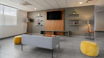 Relax in a comfortable seating area with a sofa, ottomans, and a TV for entertainment.