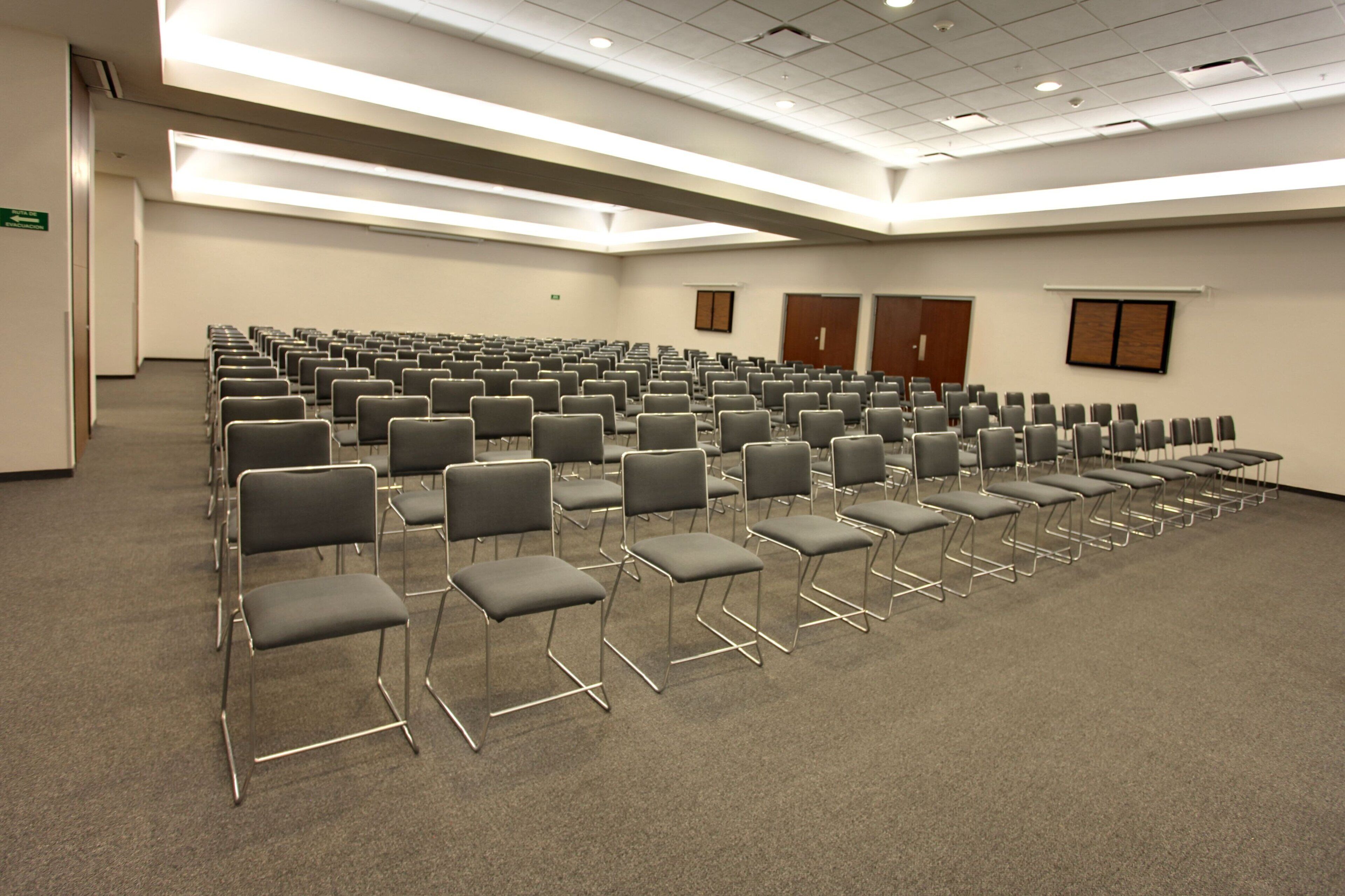A conference room with rows of chairs and a carpeted floor.