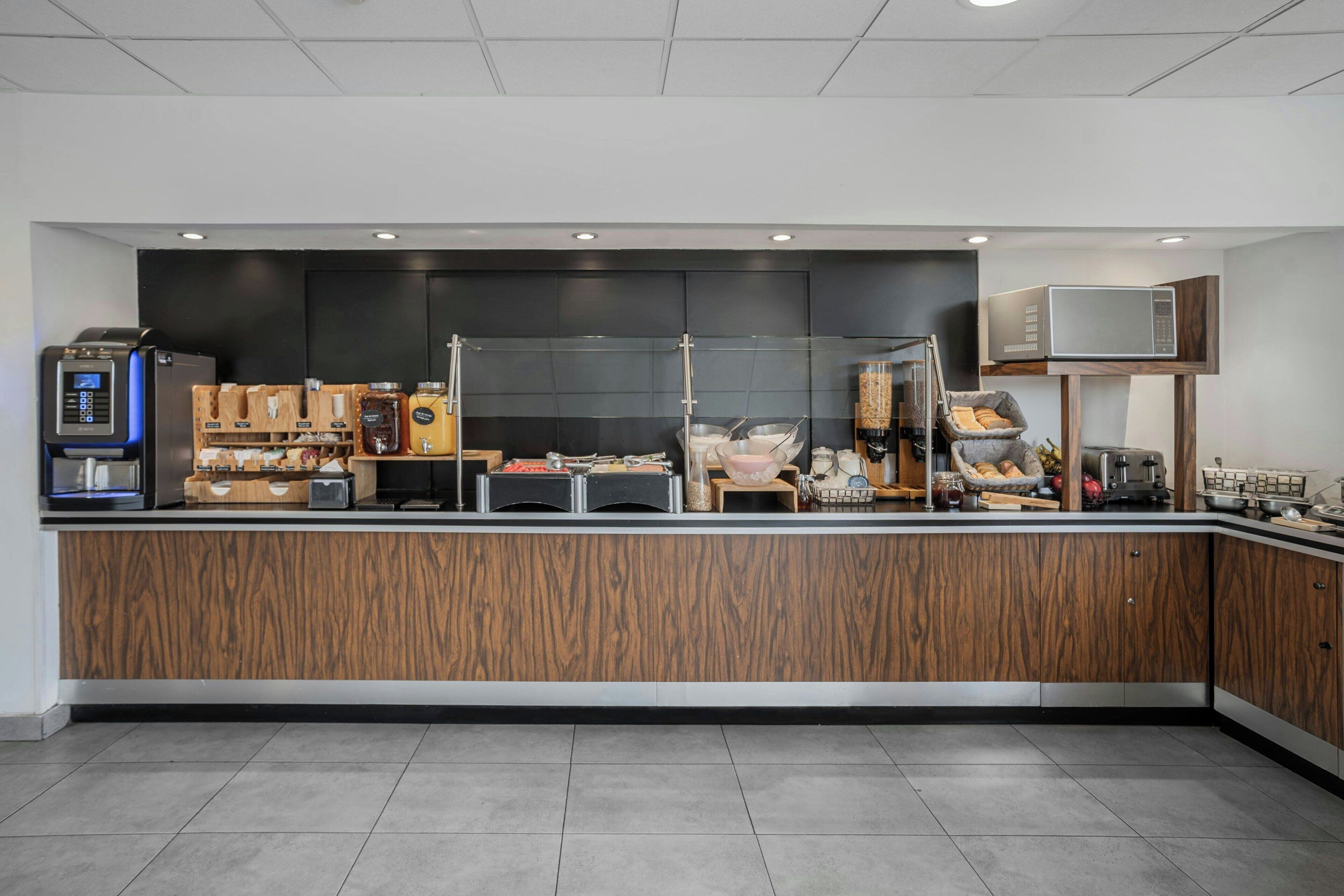 A modern kitchen area with a wooden counter, a coffee machine, and various kitchen appliances.