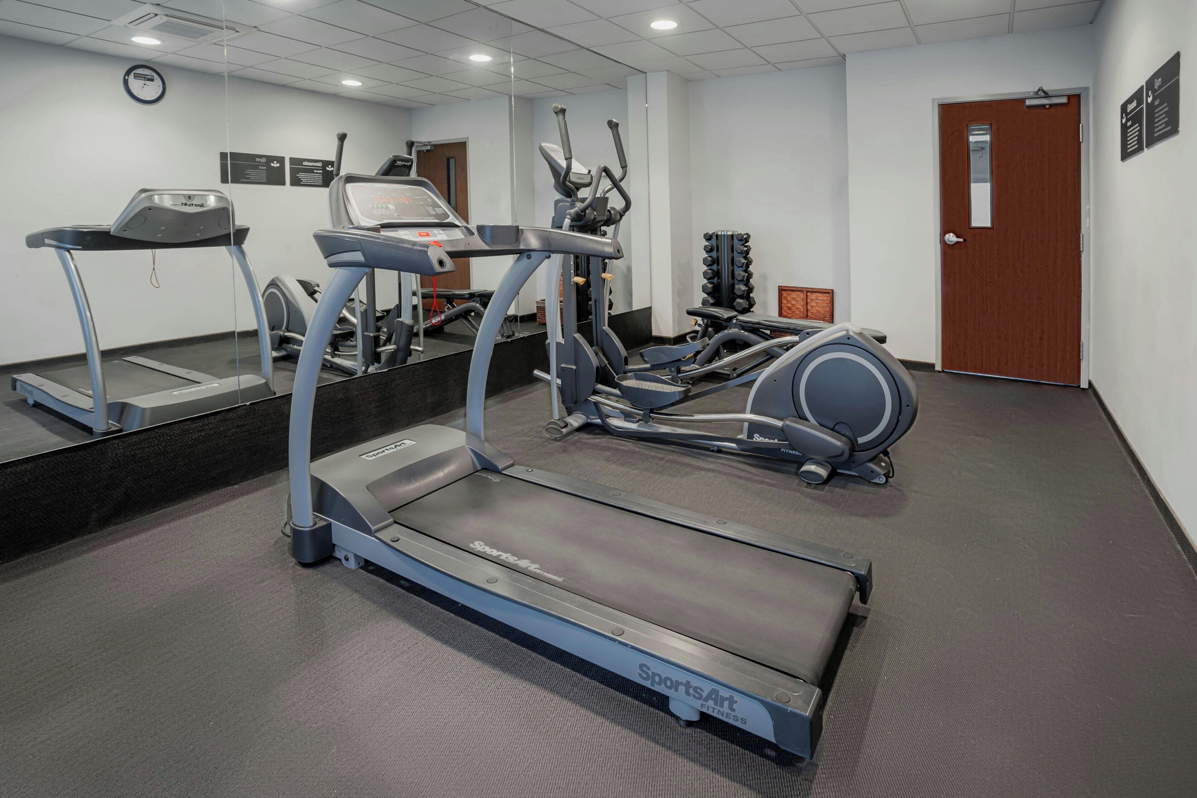 Un gimnasio con cintas de correr, elípticas y máquinas de pesas.