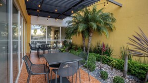 An outdoor patio with a table and chairs, surrounded by plants and a palm tree. - City Express by Marriott Durango (Durango)