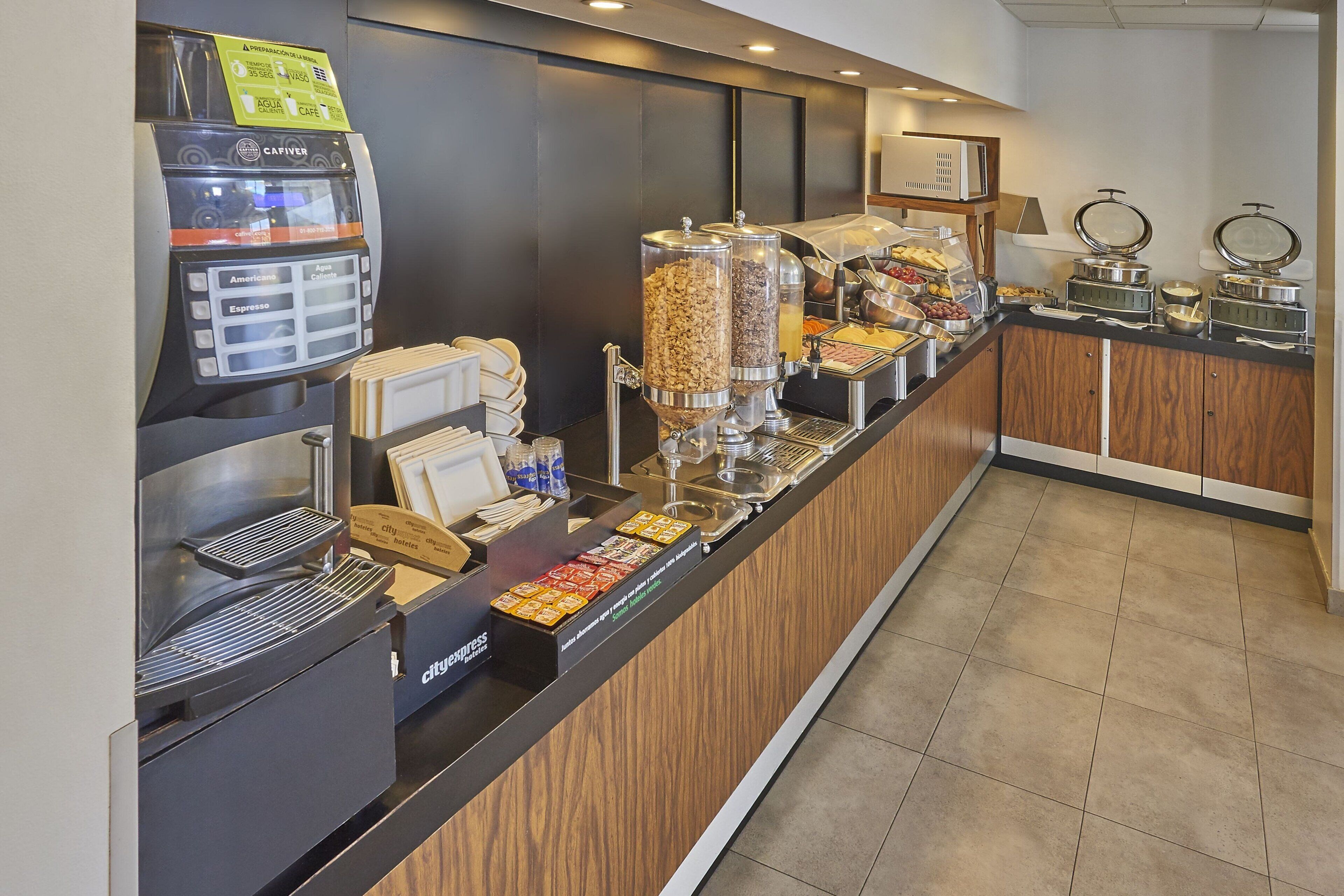 A breakfast bar with a coffee machine, a variety of food dispensers, and a microwave.
