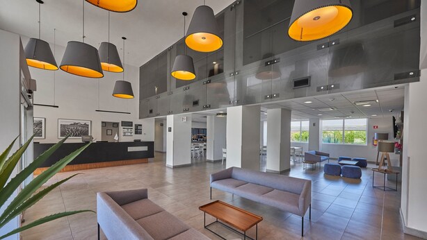 A spacious lobby with modern furniture, multiple pendant lights, and a large window providing a view of the outdoors. - City Express by Marriott Durango (Durango)