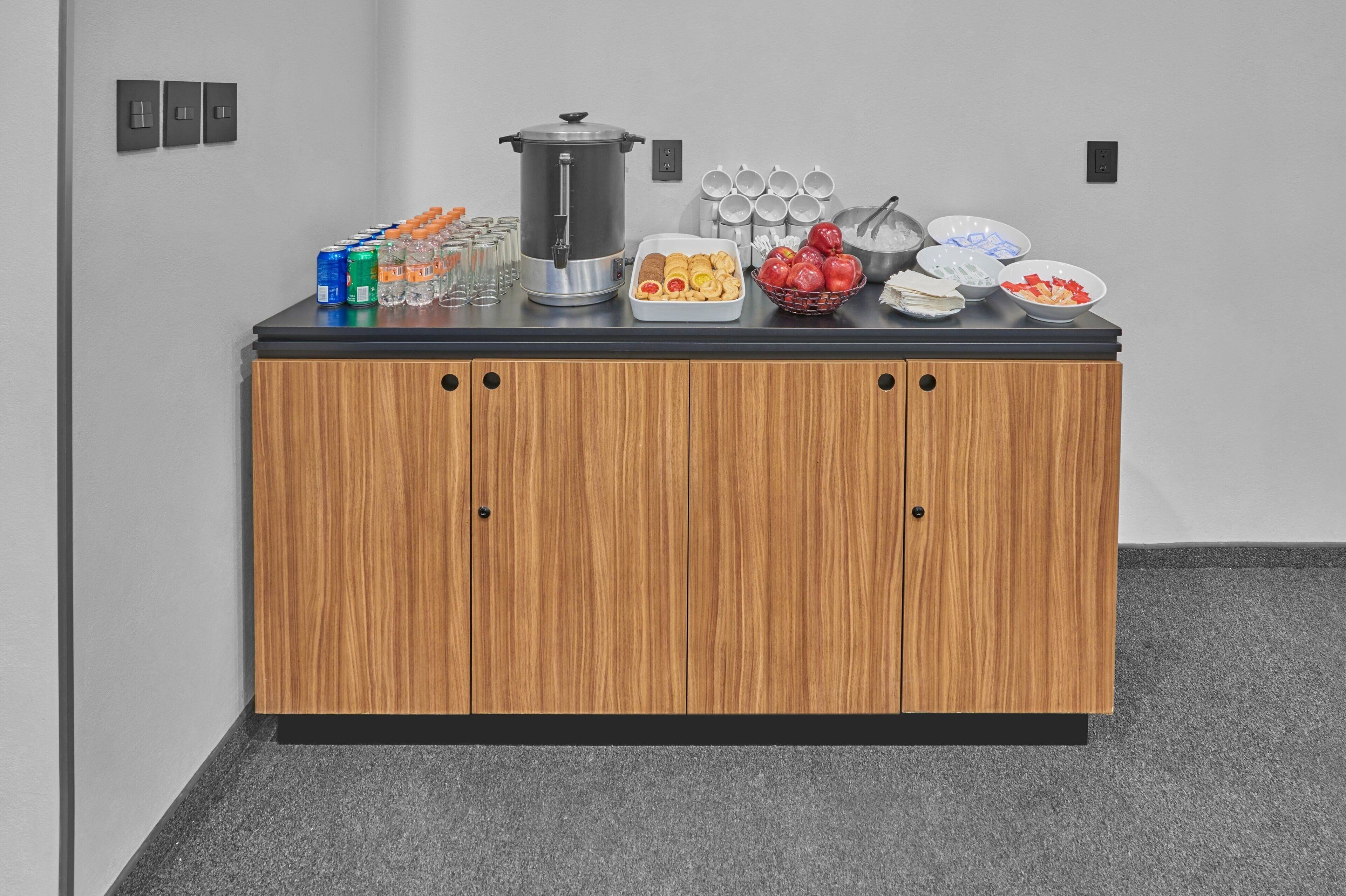 A buffet setup with a coffee station, various food items, and a water dispenser on a wooden counter.