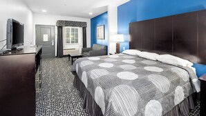 Une chambre d’hôtel équipée d’un lit, d’un bureau, d’une télévision et d’une fenêtre avec des rideaux.