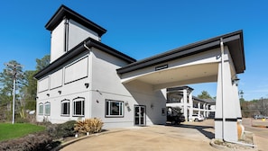 A two-story building with a covered entrance, a garage, and a clear sky. - Belmont Inn and Suites (Tatum)