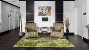 Un hall d’hôtel avec deux fauteuils, une table basse, un tableau et un comptoir de réception.