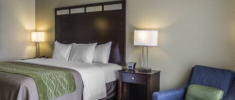 A hotel room with a bed, bedside tables, a chair, and a lamp.