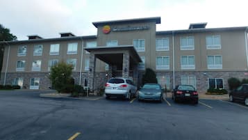 Un hotel Comfort Inn con un estacionamiento, varios coches aparcados y un cielo despejado.