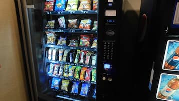 Un distributeur automatique rempli de diverses collations et boissons, notamment des chips et des sodas.