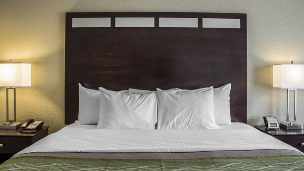 Une chambre d’hôtel avec un grand lit, deux tables de chevet, une petite table et une lampe fixée au mur.