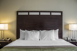 A hotel room with a large bed, two bedside tables, a nightstand, and a wall-mounted lamp. - Comfort Inn St. Clairsville (St. Clairsville)