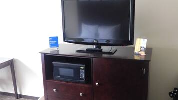 A dark wooden cabinet with a flat-screen TV and a microwave on top.