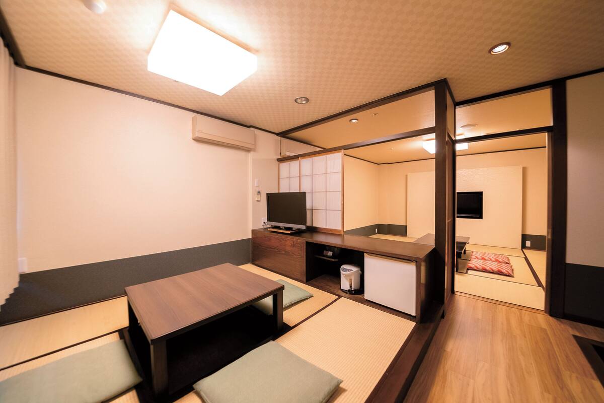 A compact hotel room with a kitchenette, a small dining area, and a sliding door leading to a bathroom.