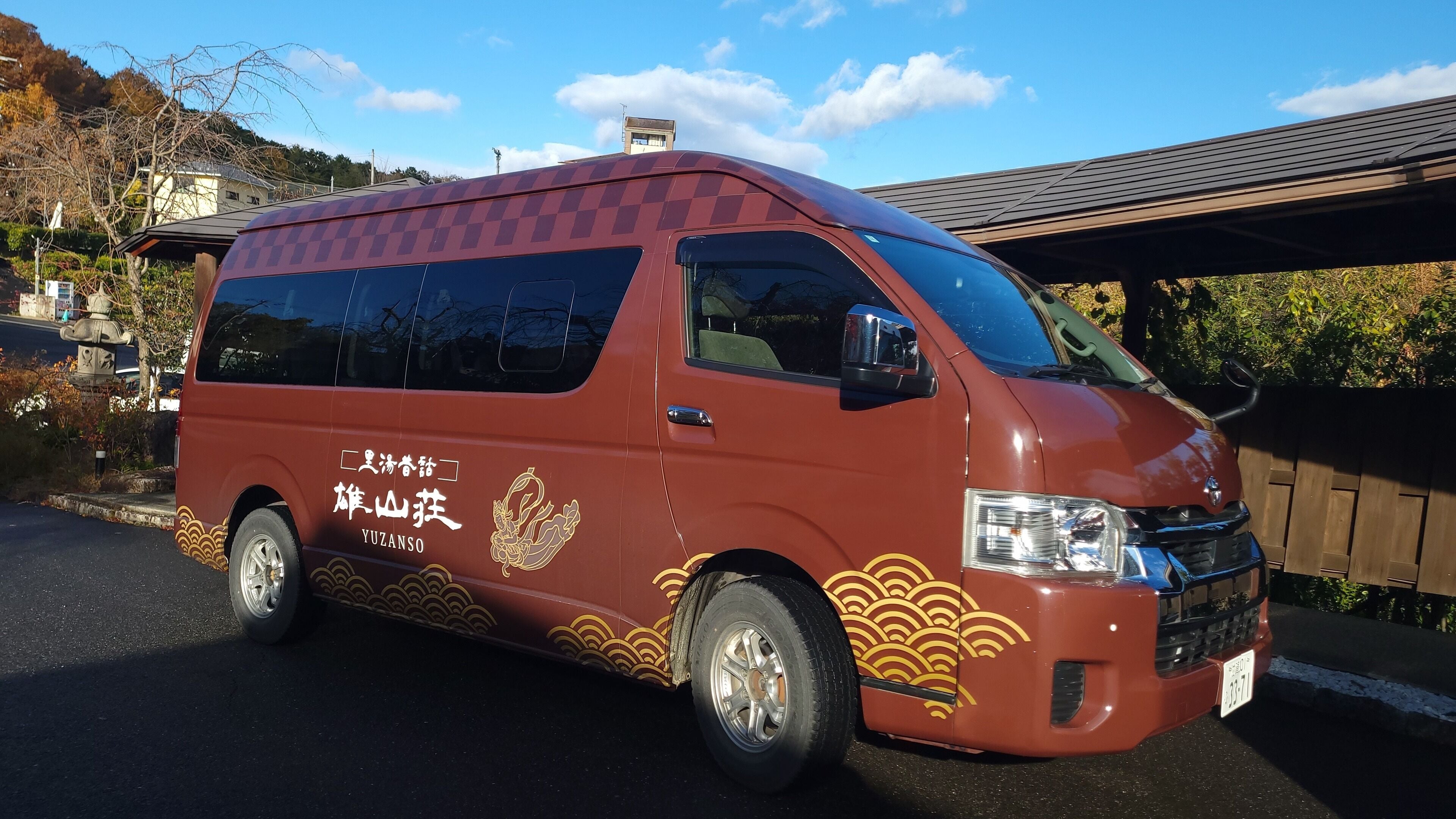 A red van with gold wave patterns and Chinese characters parked on a street.
