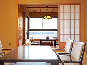 A room with a large table and chairs, a view of the sea through a large window, and traditional Japanese sliding doors. - Satoyu Mukashibanashi Yuzanso Ryokan (Otsu)