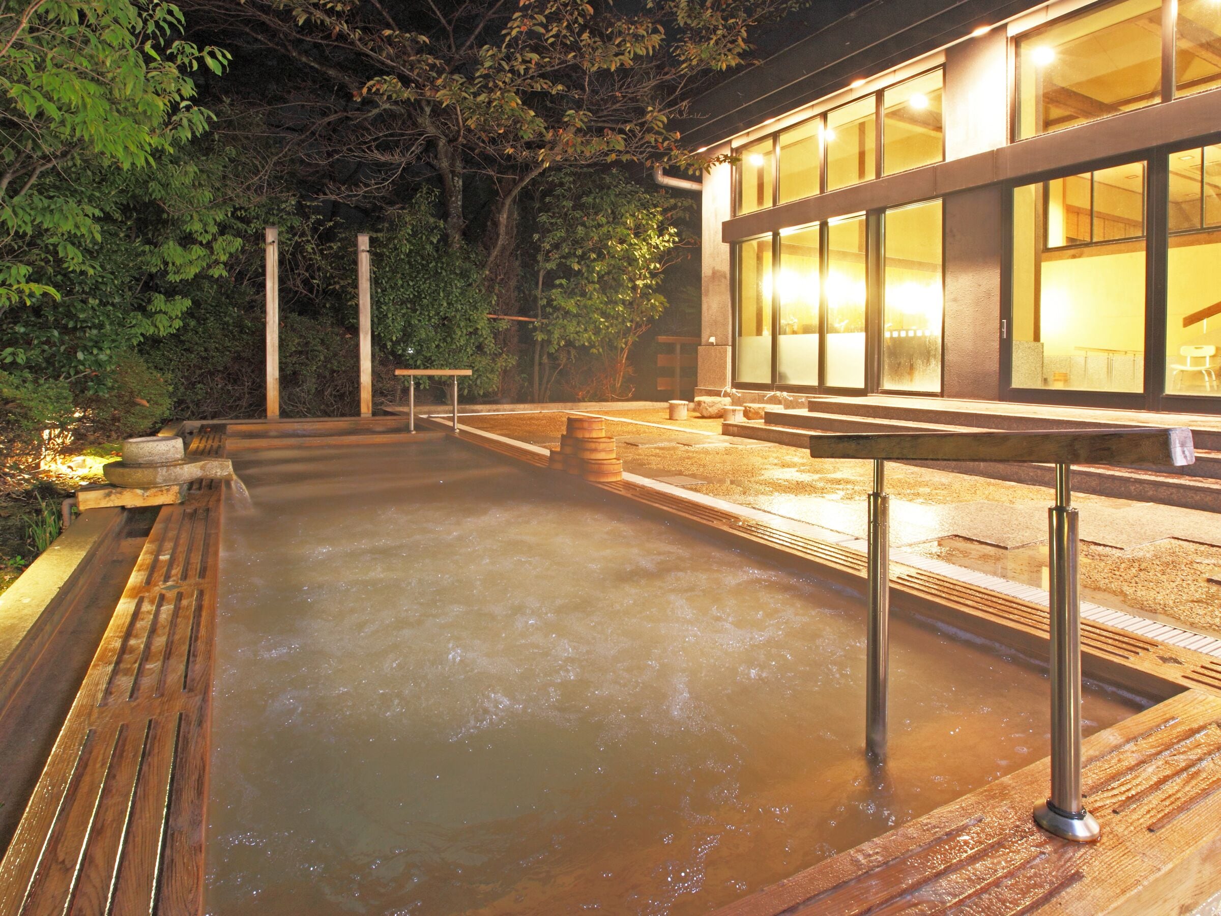 Un área de aguas termales con bancos de madera y una plataforma de piedra.