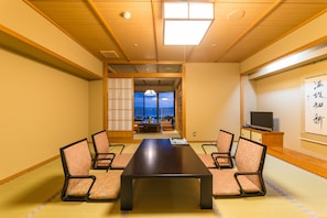 A traditional Japanese room with tatami flooring, a low table, and four chairs.