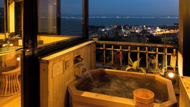 A wooden hot tub with a view of a cityscape at dusk. - Satoyu Mukashibanashi Yuzanso Ryokan (Otsu)