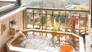 A hot tub with a wooden exterior and a view of a cityscape through a large window. - Satoyu Mukashibanashi Yuzanso Ryokan (Otsu)
