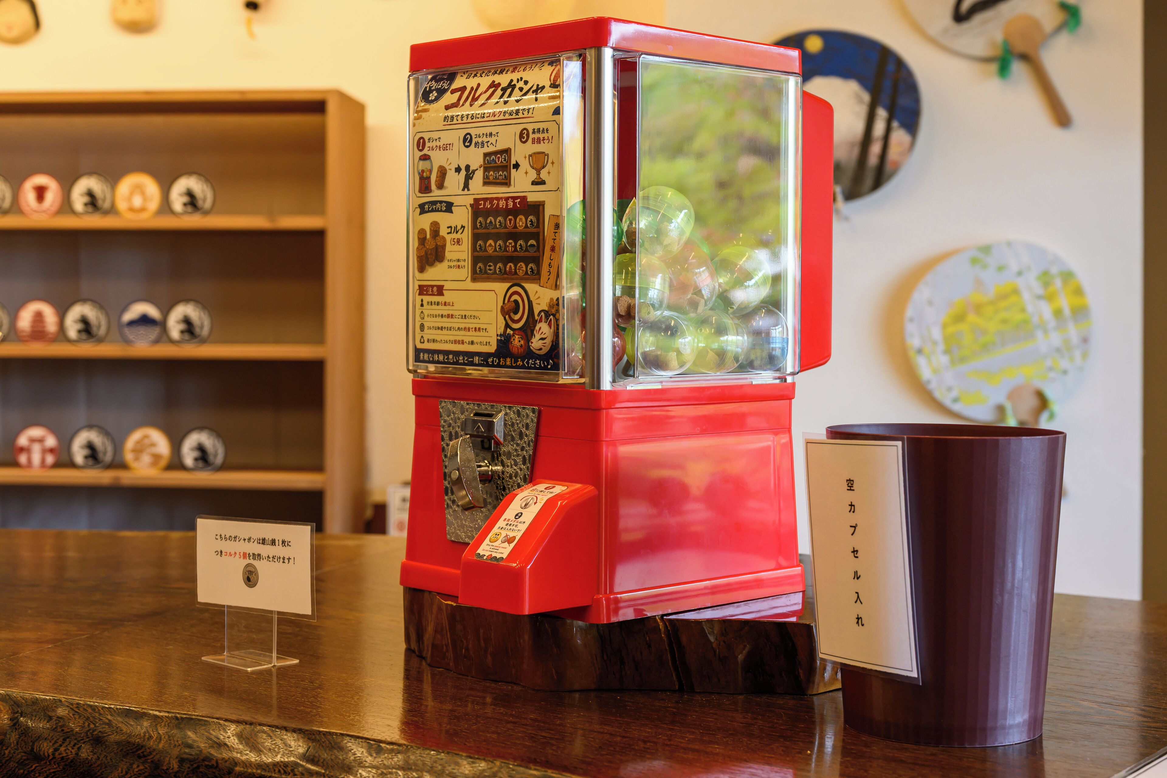 A red vending machine with Japanese text, a wooden shelf with various items, and a brown mug on the counter.