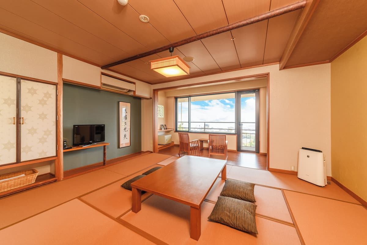 A traditional Japanese room with tatami flooring, a low wooden table, a television, and a sliding door.