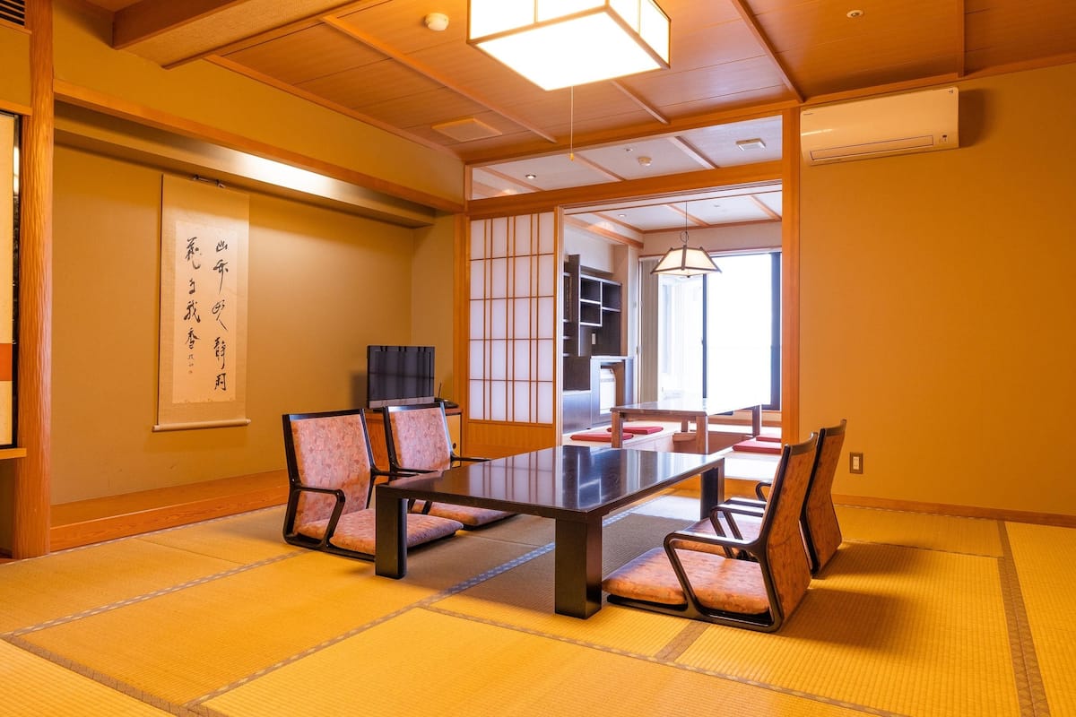 A traditional Japanese room with tatami flooring, a low table, and four chairs.