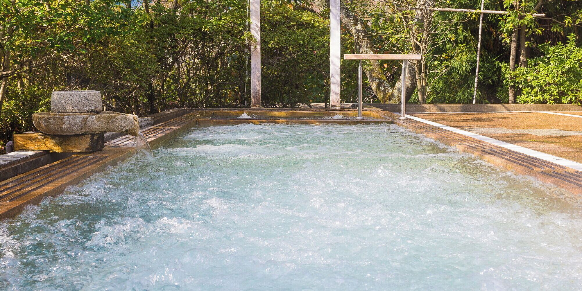 A hot spring area with a wooden deck and stone structures.