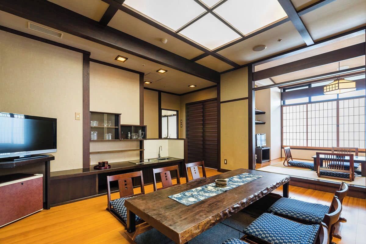 A traditional Japanese-style room with tatami flooring, a low table, and a television.