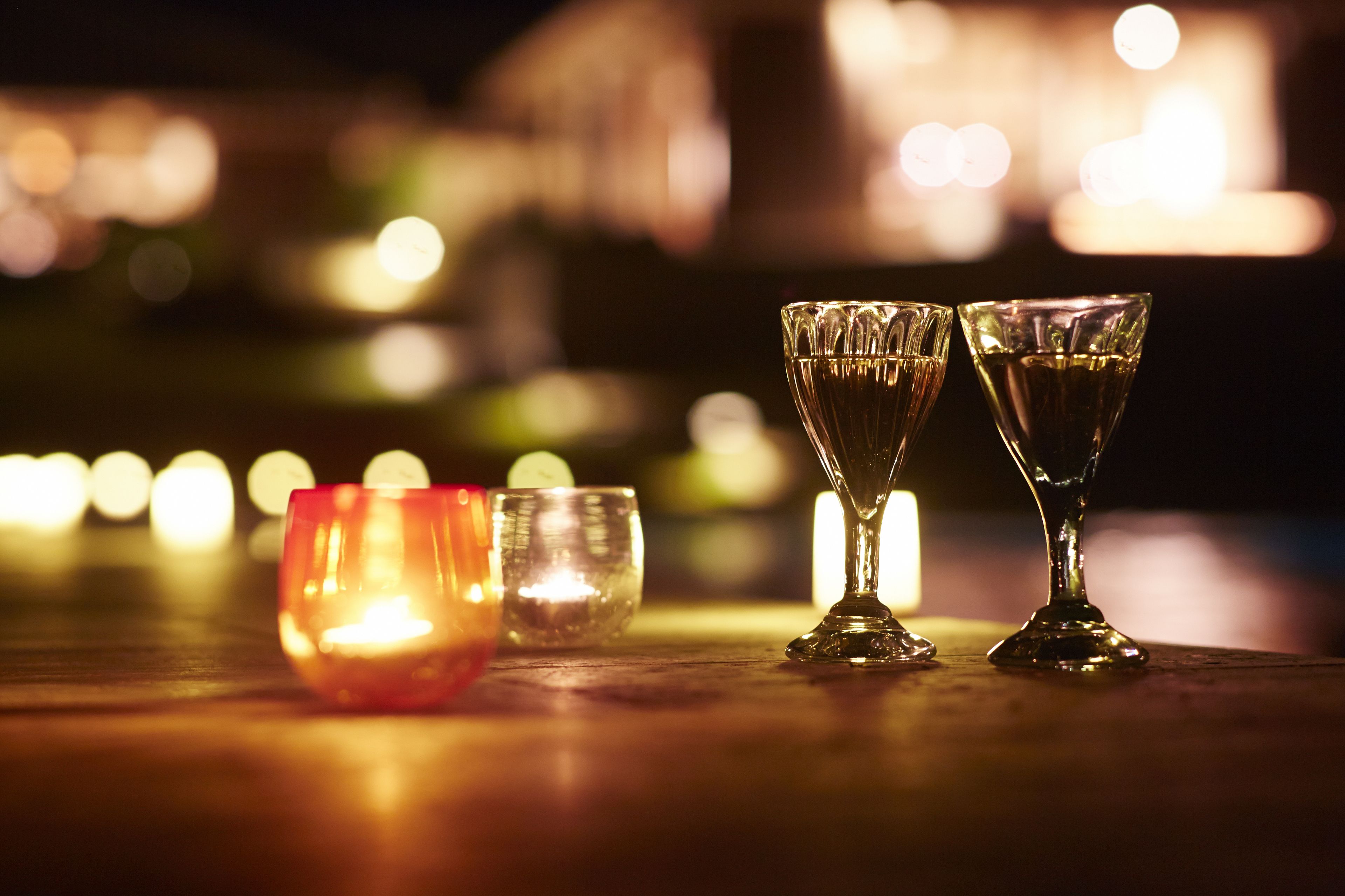 Three glasses on a table with blurred lights in the background.