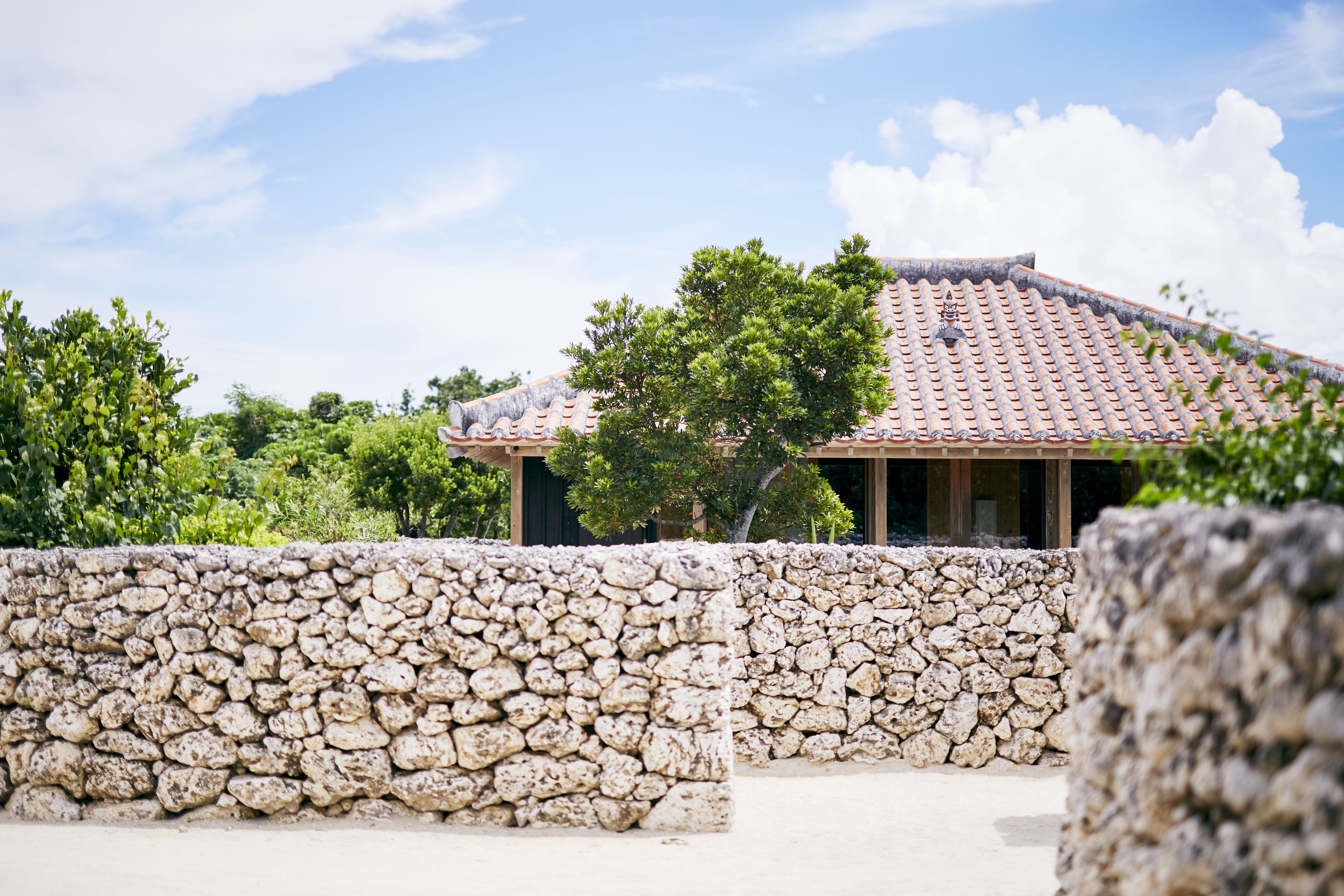 A traditional building with a tiled roof, surrounded by stone walls and lush greenery.