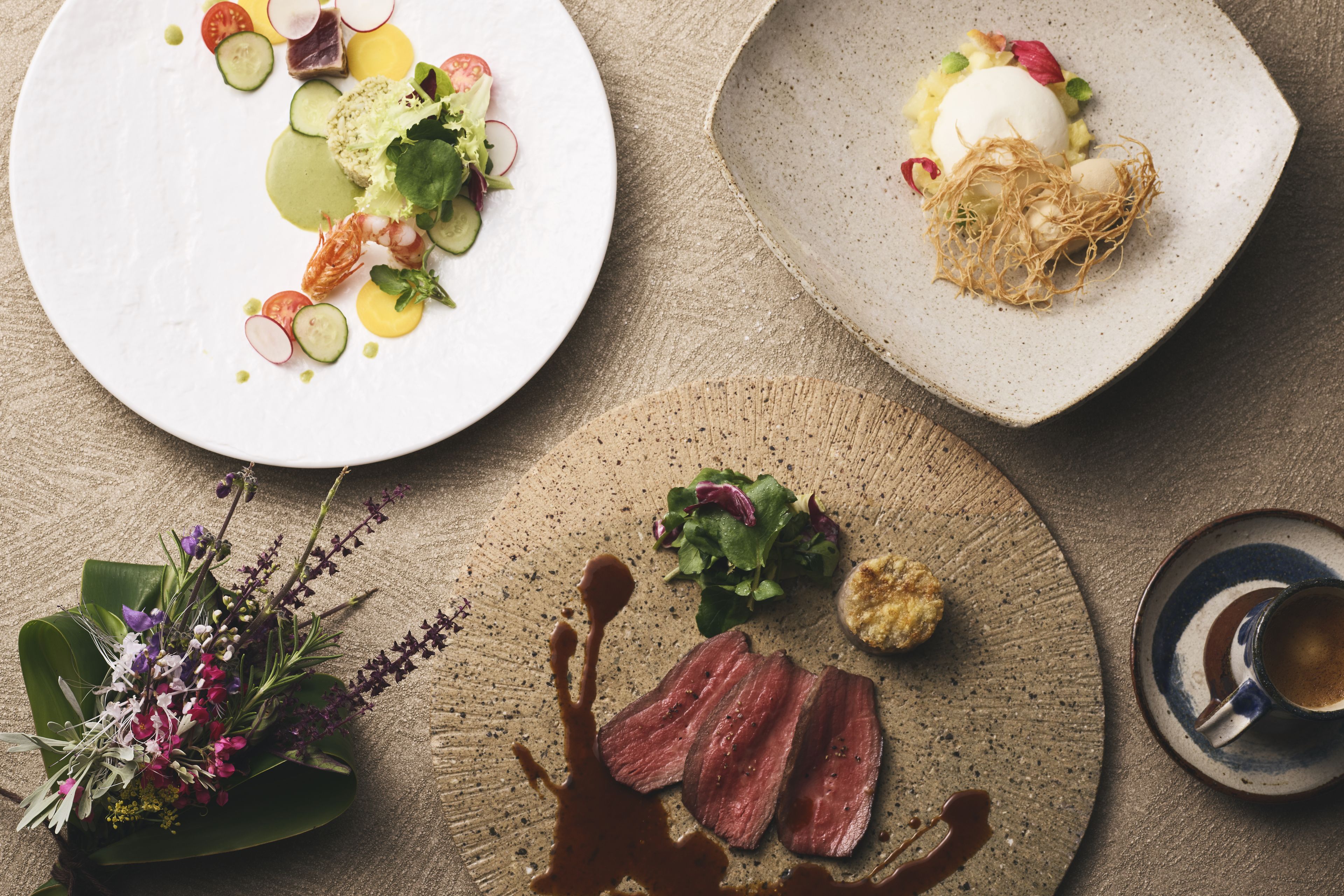 A dining table with various dishes, including a plate with sliced meat, a plate with a poached egg, and a plate with a salad.