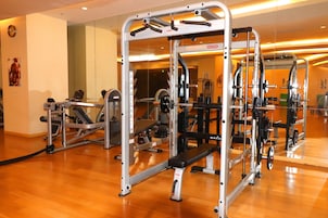 A gym with various exercise machines, a bench, and a mirror on the wall.