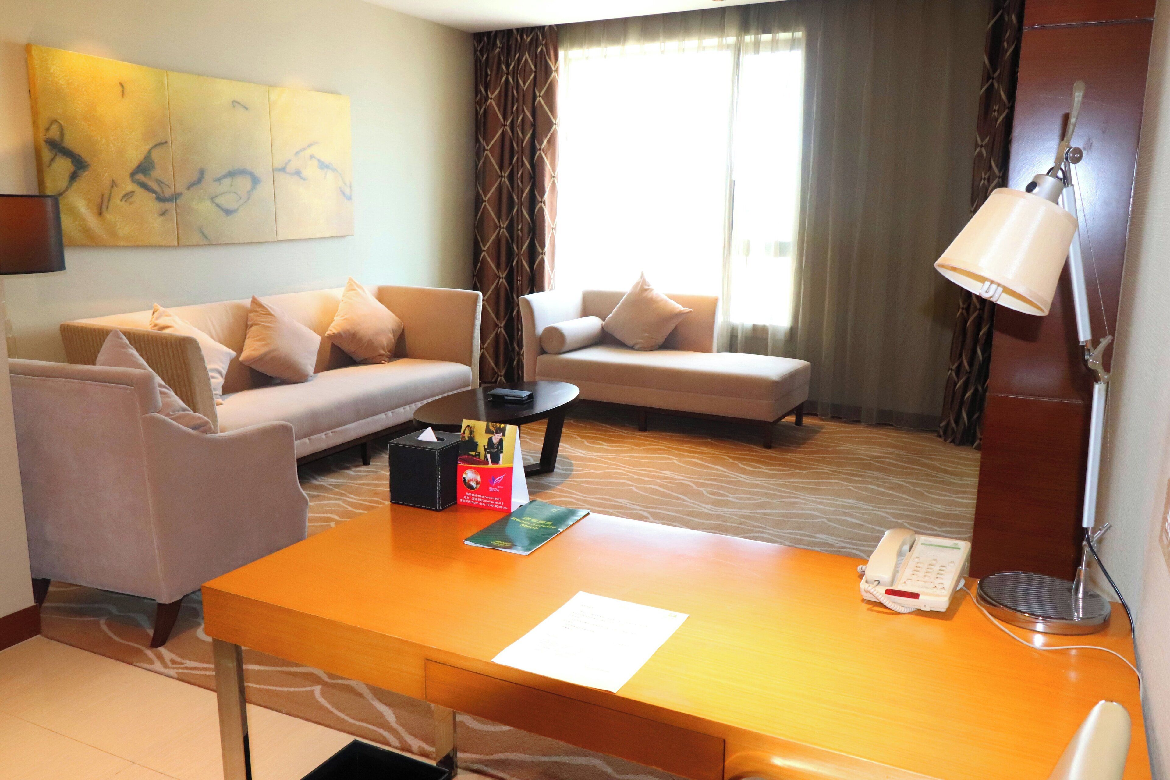 Habitación de hotel con sofá, un escritorio de madera con teléfono y lámpara, y un cuadro abstracto grande en la pared.