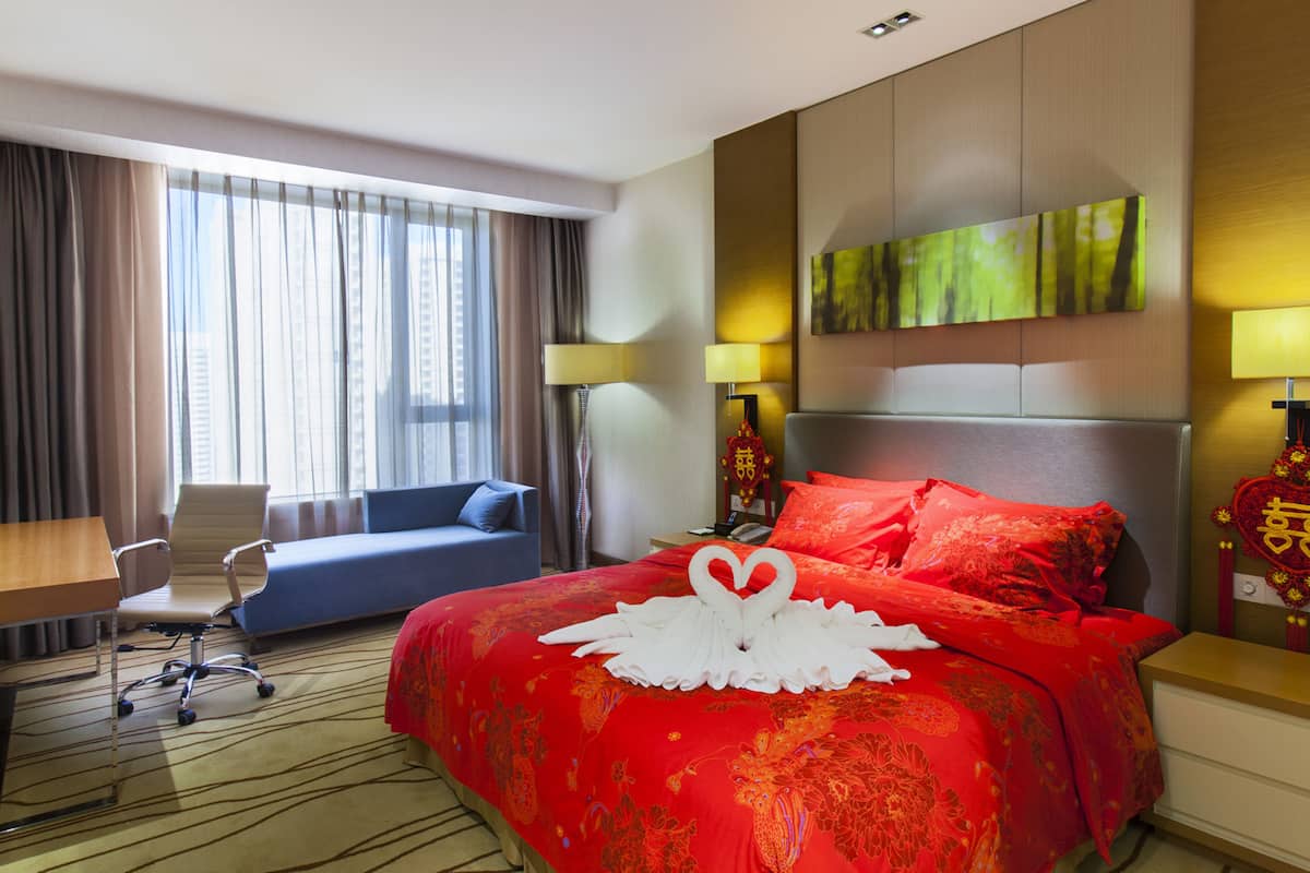 A hotel room with a large bed, a desk, a chair, and a sofa.