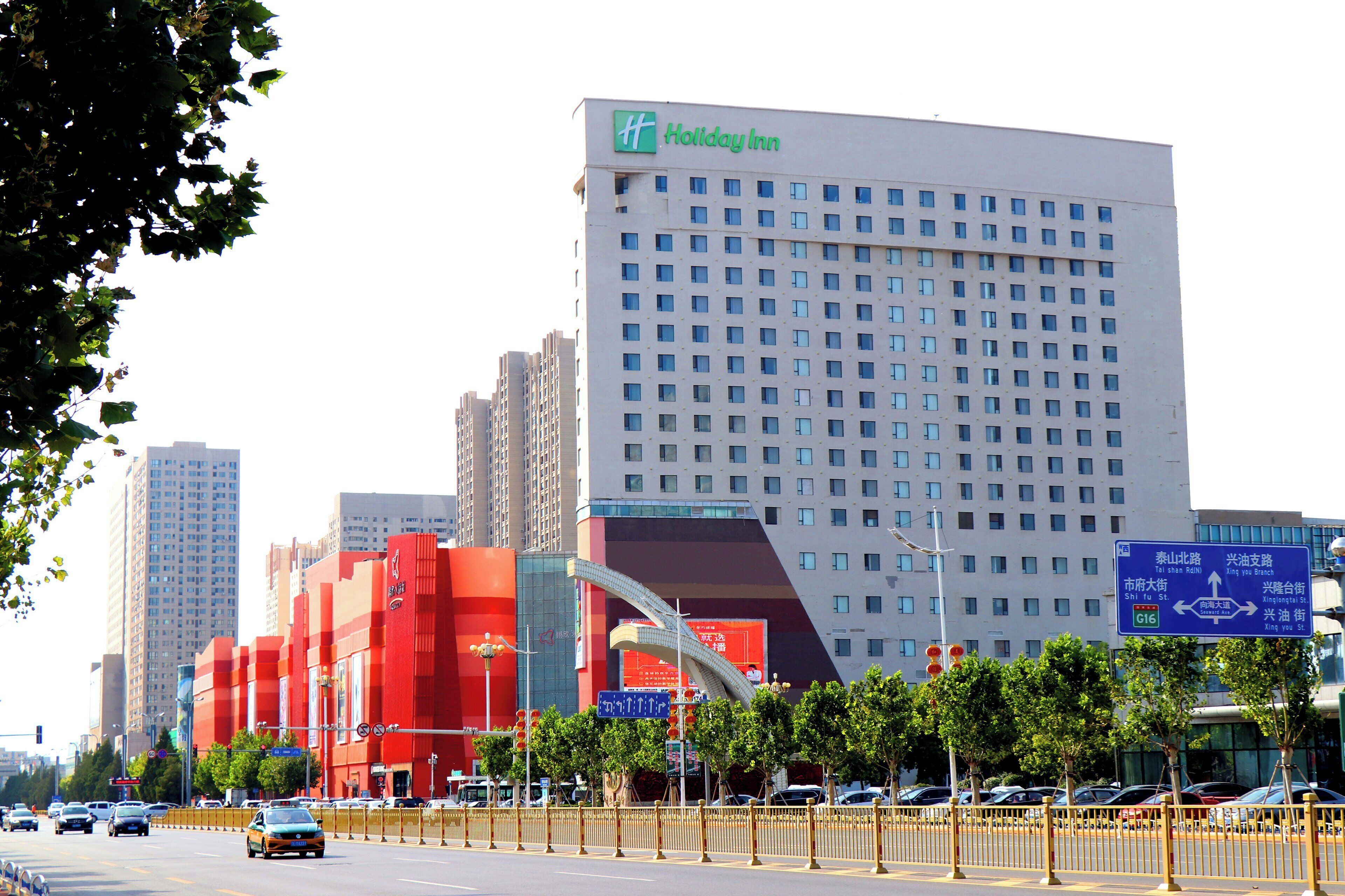 Ein Holiday Inn Hotel mit modernem Design, erkennbar an seiner auffälligen roten Fassade und dem großen Glaseingang.