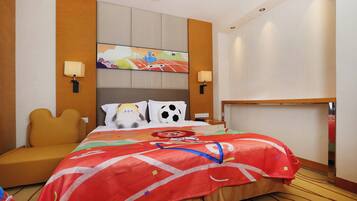 Una habitación de hotel con cama, sofá, cabecera con pintura, dos lámparas de pared y mesita de noche.