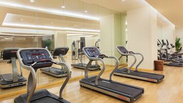 Un gimnasio con cintas de correr, equipo de ejercicio y piso de madera.