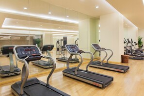 A gym with multiple treadmills, exercise equipment, and a wooden floor. - Holiday Inn Panjin Aqua City by IHG (Panjin)