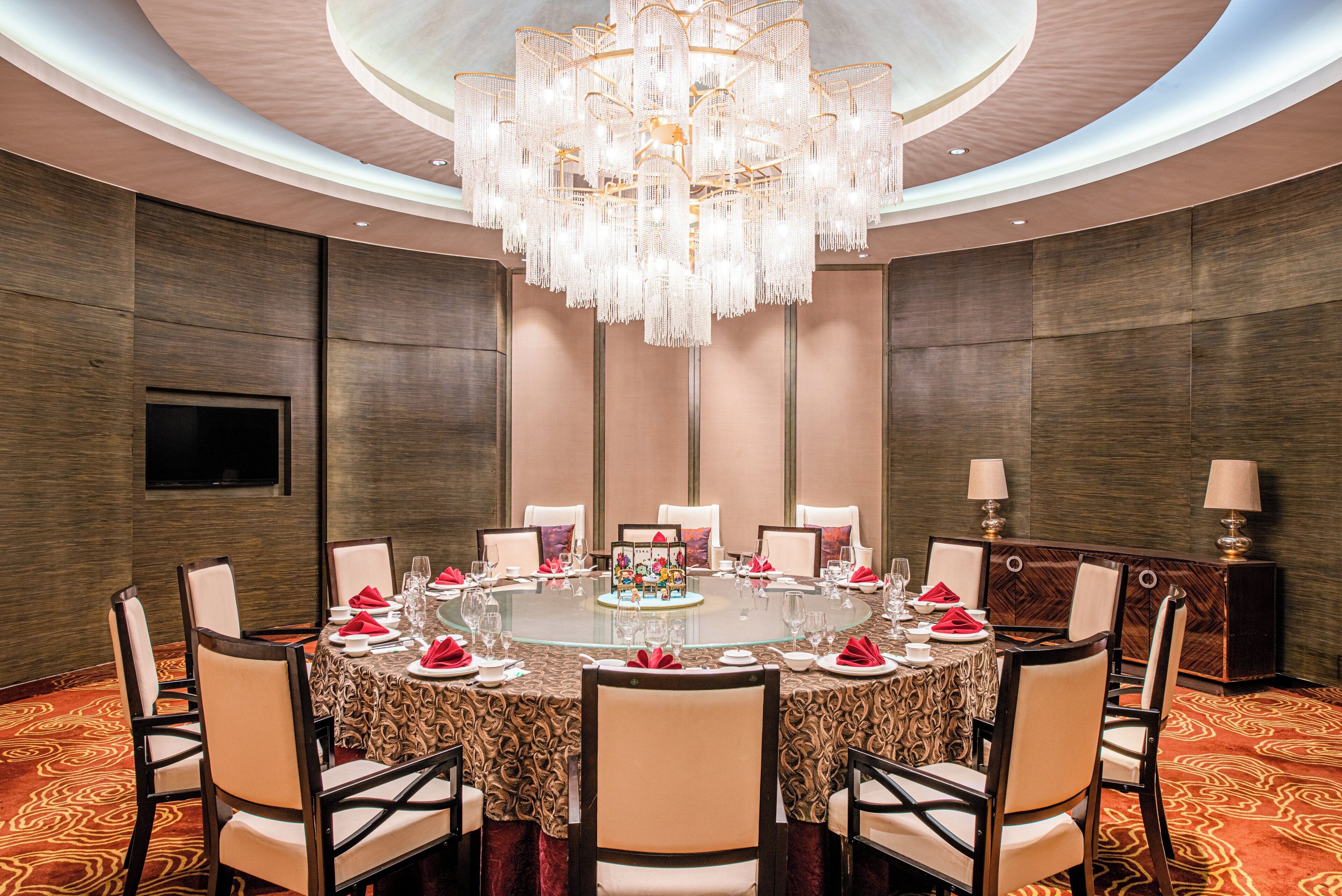 A formal dining room with a round table, chairs, and a chandelier.
