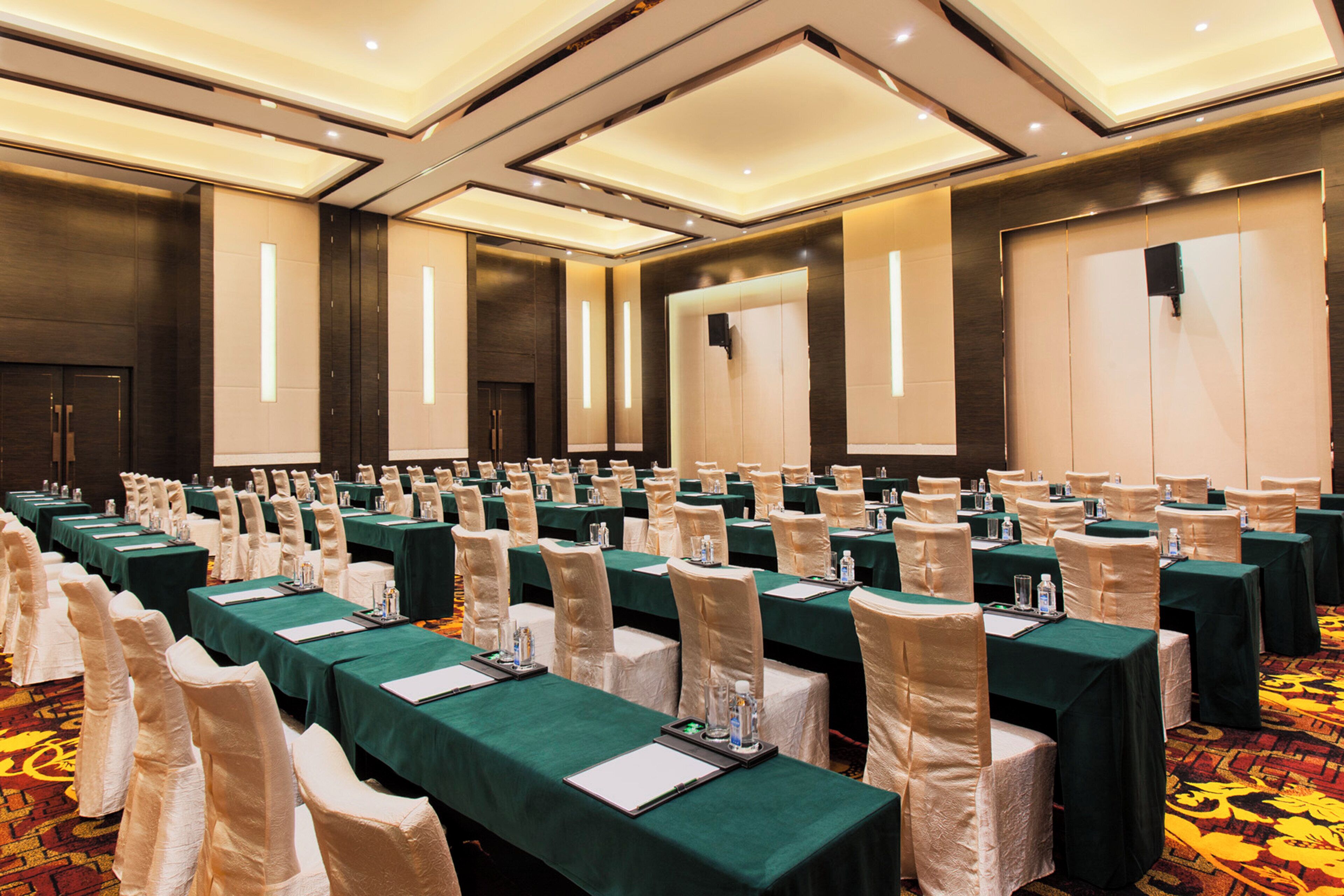A conference room with rows of tables, chairs, and a carpeted floor.