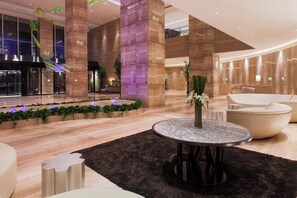 A modern lobby with a central seating area, a reception desk, and a plant arrangement. - Holiday Inn Panjin Aqua City by IHG (Panjin)