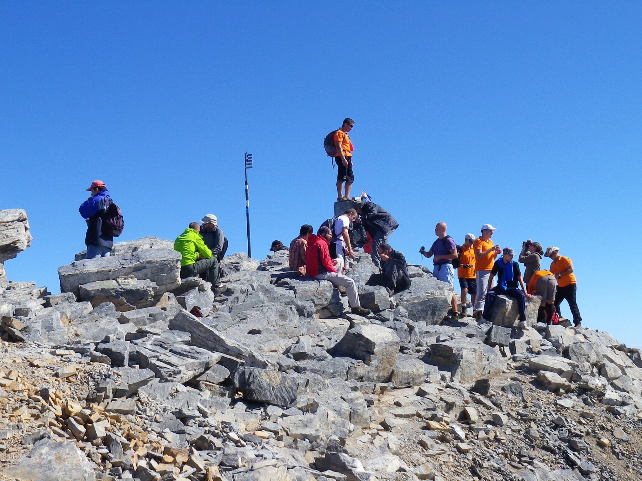 Een groep mensen op een rotsachtige bergtop met een heldere lucht.